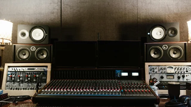 A treated recording studio control room with monitor speakers and acoustic panels.